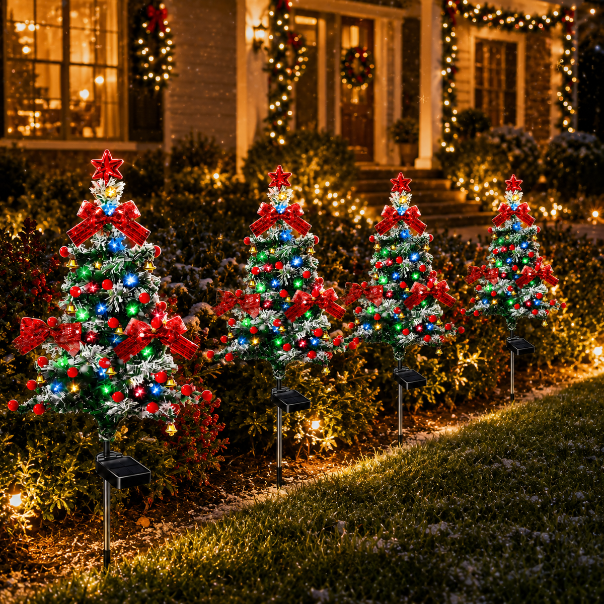 Four matching solar Christmas trees arranged in a garden bed